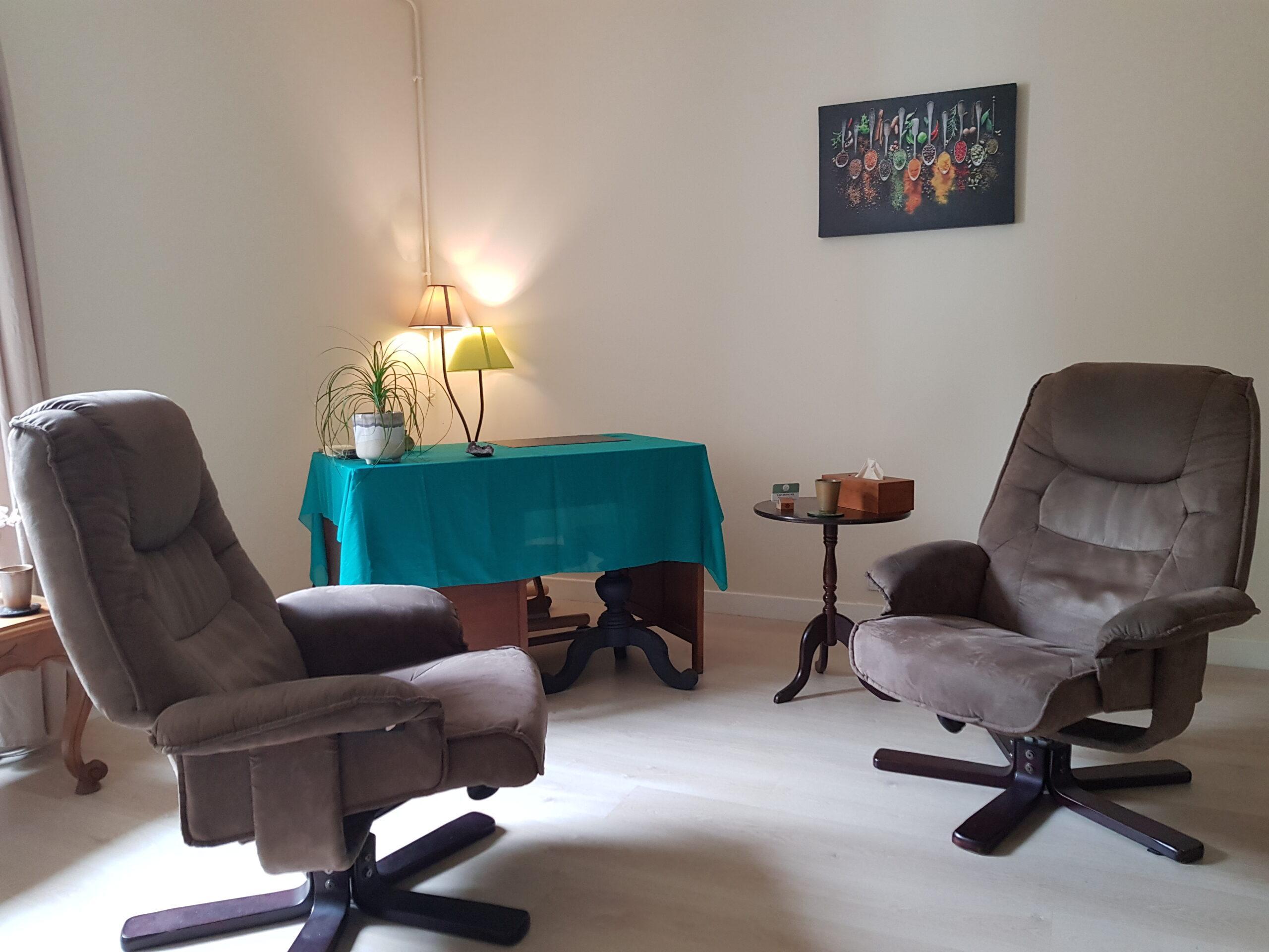 Cette photo présente un cabinet de consultation avec deux fauteuils marrons en premier plan, un bureau en second plan et un tableau au mur.